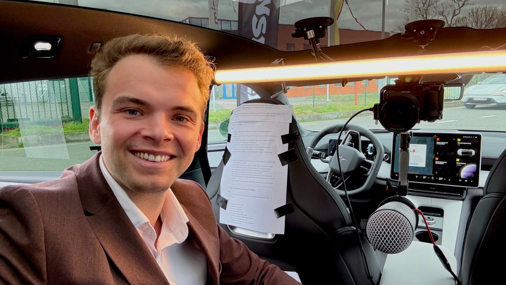 Wout in a PoleStar taking a selfie with in the background an entire in-car tv studio setup with microphones, cameras and a script.