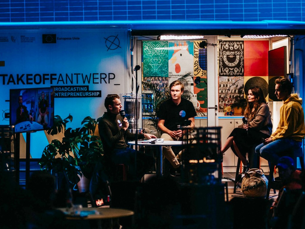 Wout in a virtual/hybrid setup in which he is interviewing 4 other participants in a live-streaming studio.